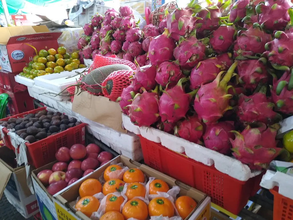 A fruit stall at Phnom Penh Central Market piled with dragon fruit, mandarins and melons in crates