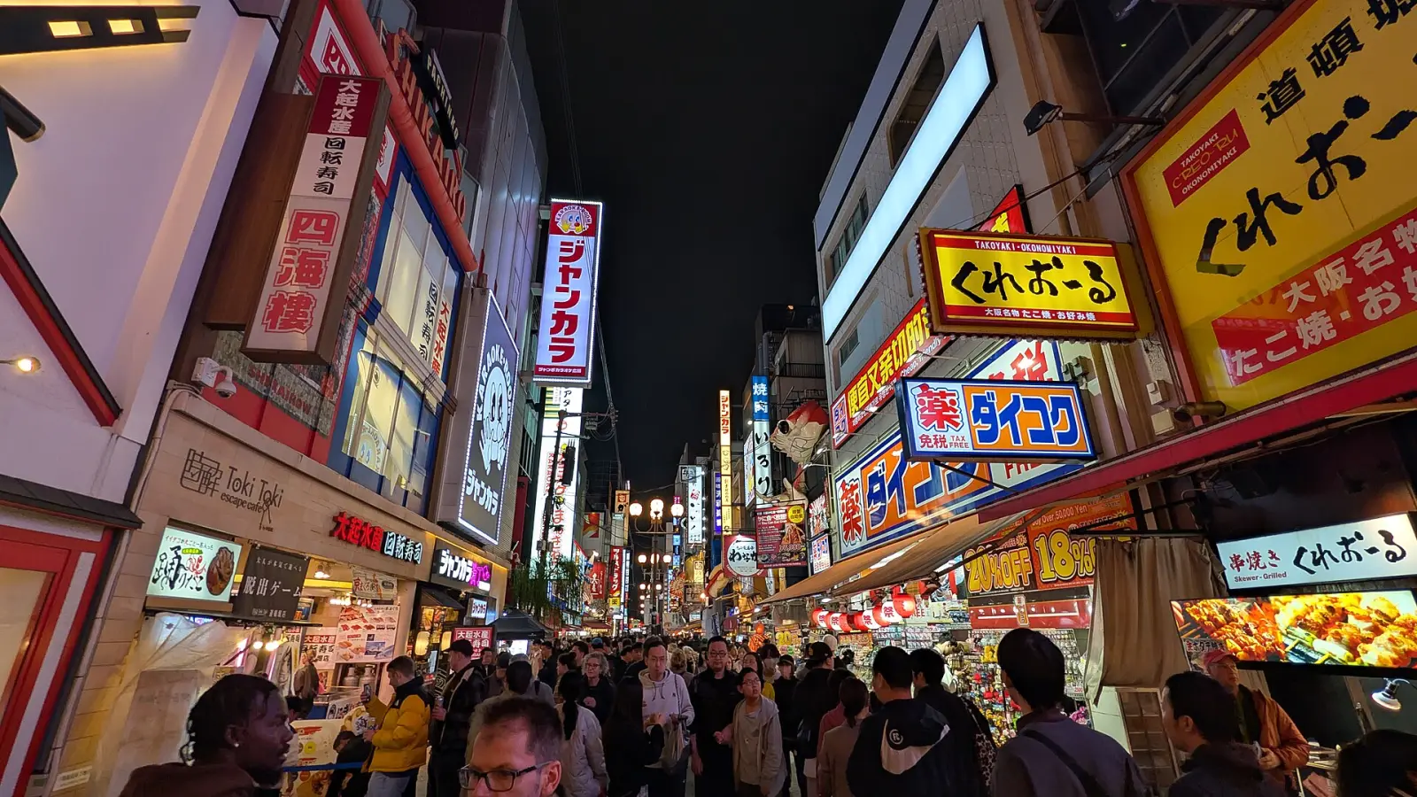 A street in Dotonbori, Osaka, lit by signs and restaurant fronts at night