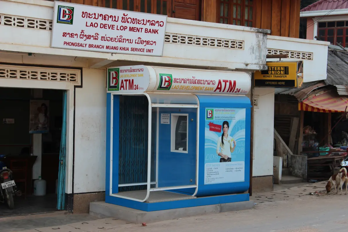 A single Lao Development Bank ATM booth on a quiet street in Muang Khua, with a Western Union sign next door