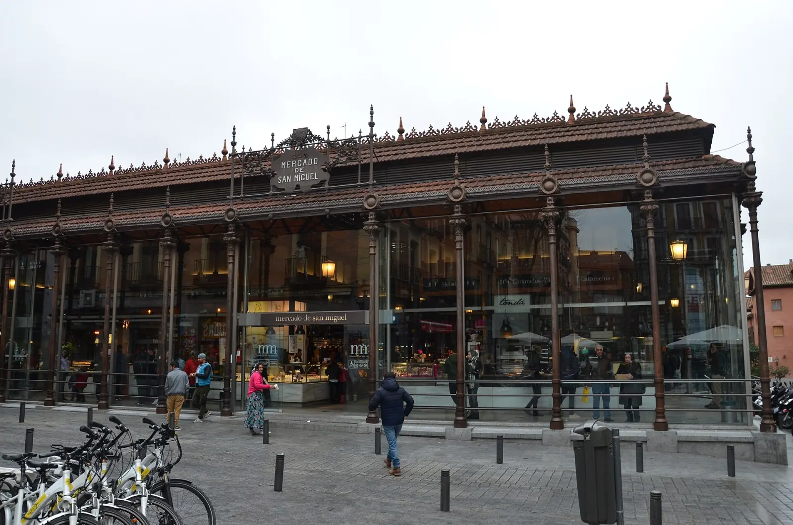 Inside the Mercado de San Miguel in Madrid, iron-and-glass hall with food counters and crowds